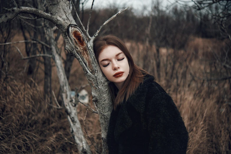 a woman wearing black in the woods near trees