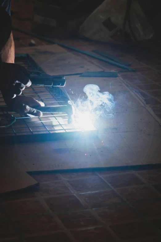 welder grinding a metal on a piece of tile