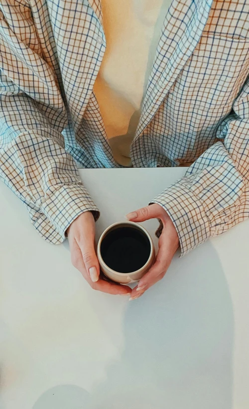 a person in plaid shirt and glasses holding a cup