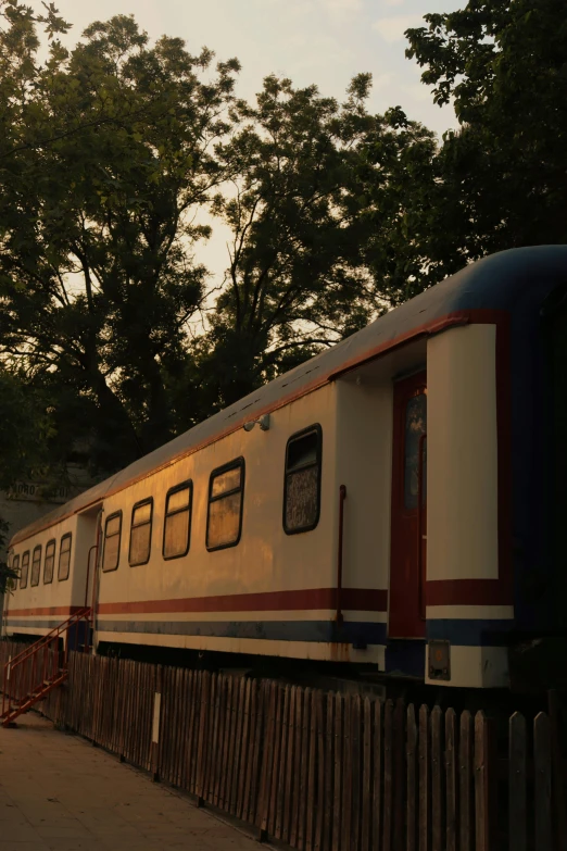 a white and red train sitting next to trees