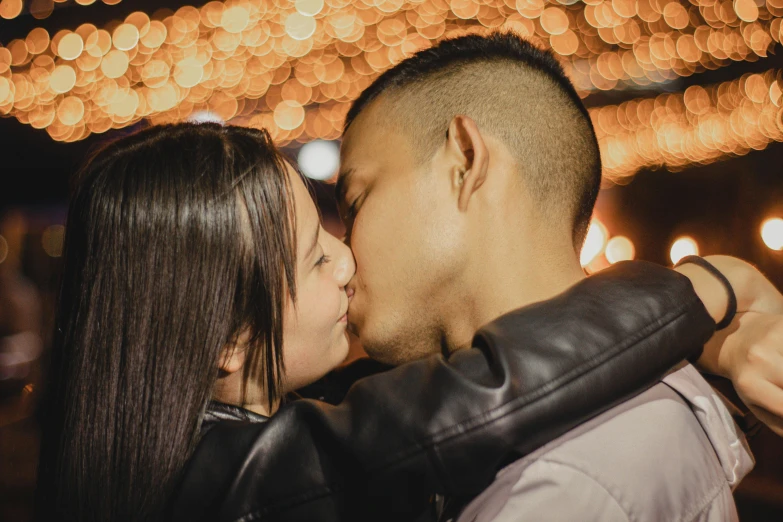 man kissing woman in front of some lights