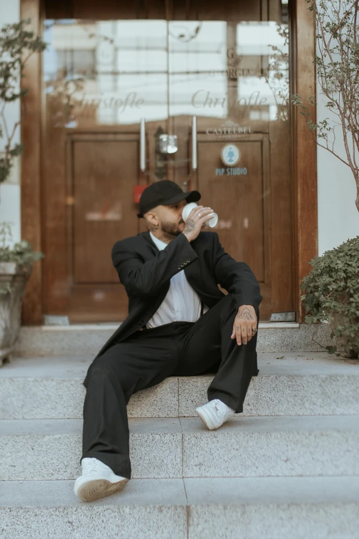 a man sitting on steps holding a bottle in his hand