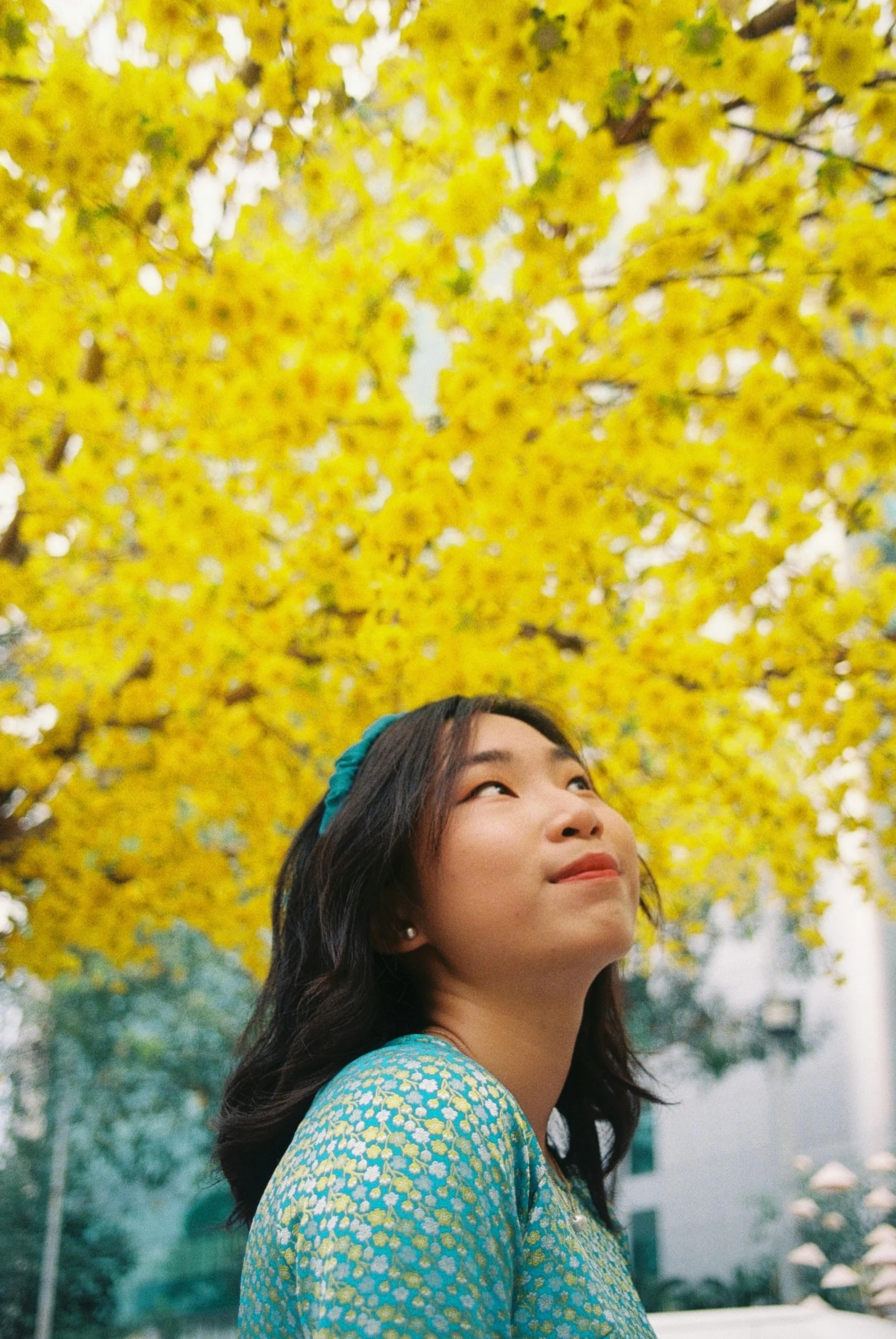  in a turquoise dress standing beneath yellow tree