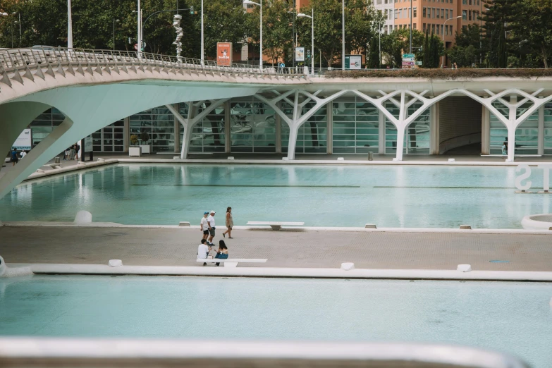 two people on a skate board near a large swimming pool