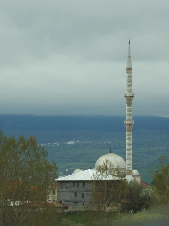 a large white building stands on a hill in the distance