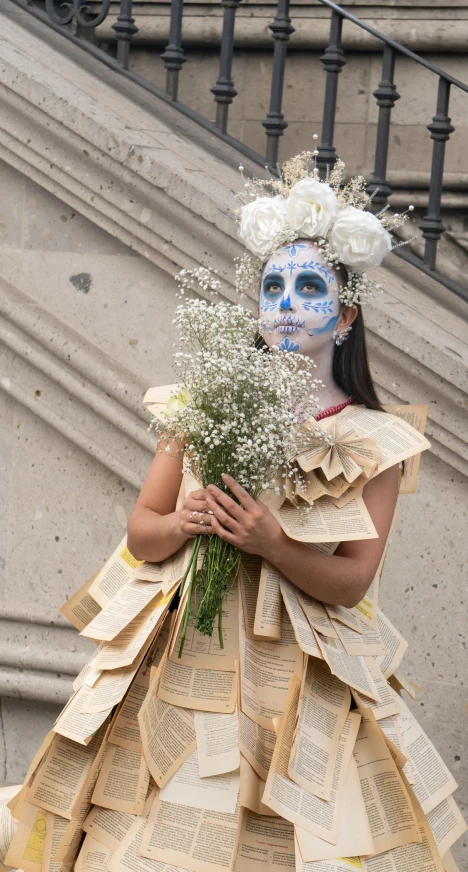 a woman in paper dress with her face painted like a skull