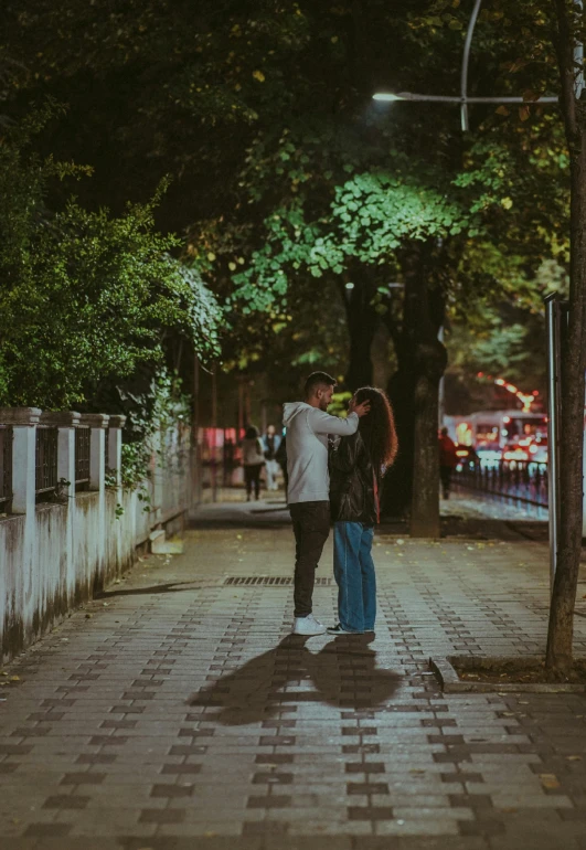 a couple kissing on a city street at night