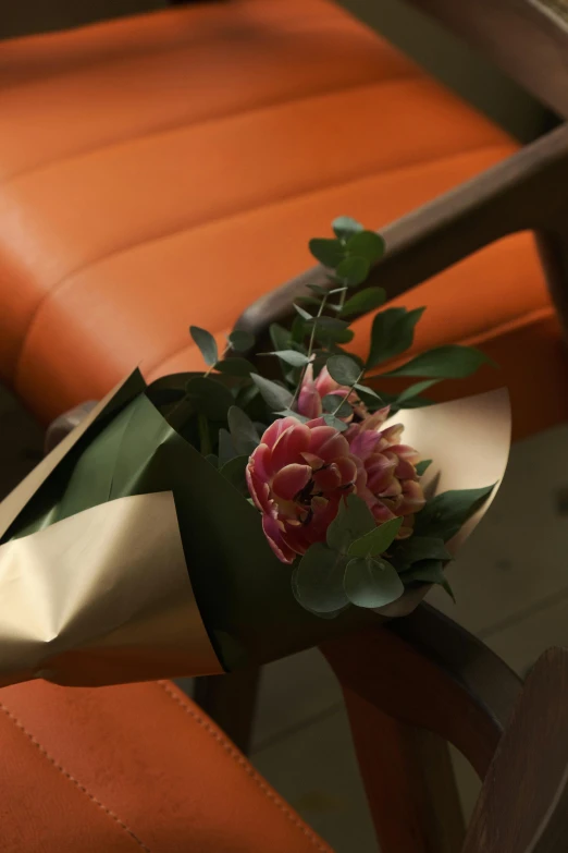 a bouquet of flowers in a metallic vase on a brown chair