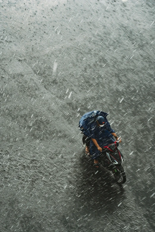 two people ride a motorcycle through the rain