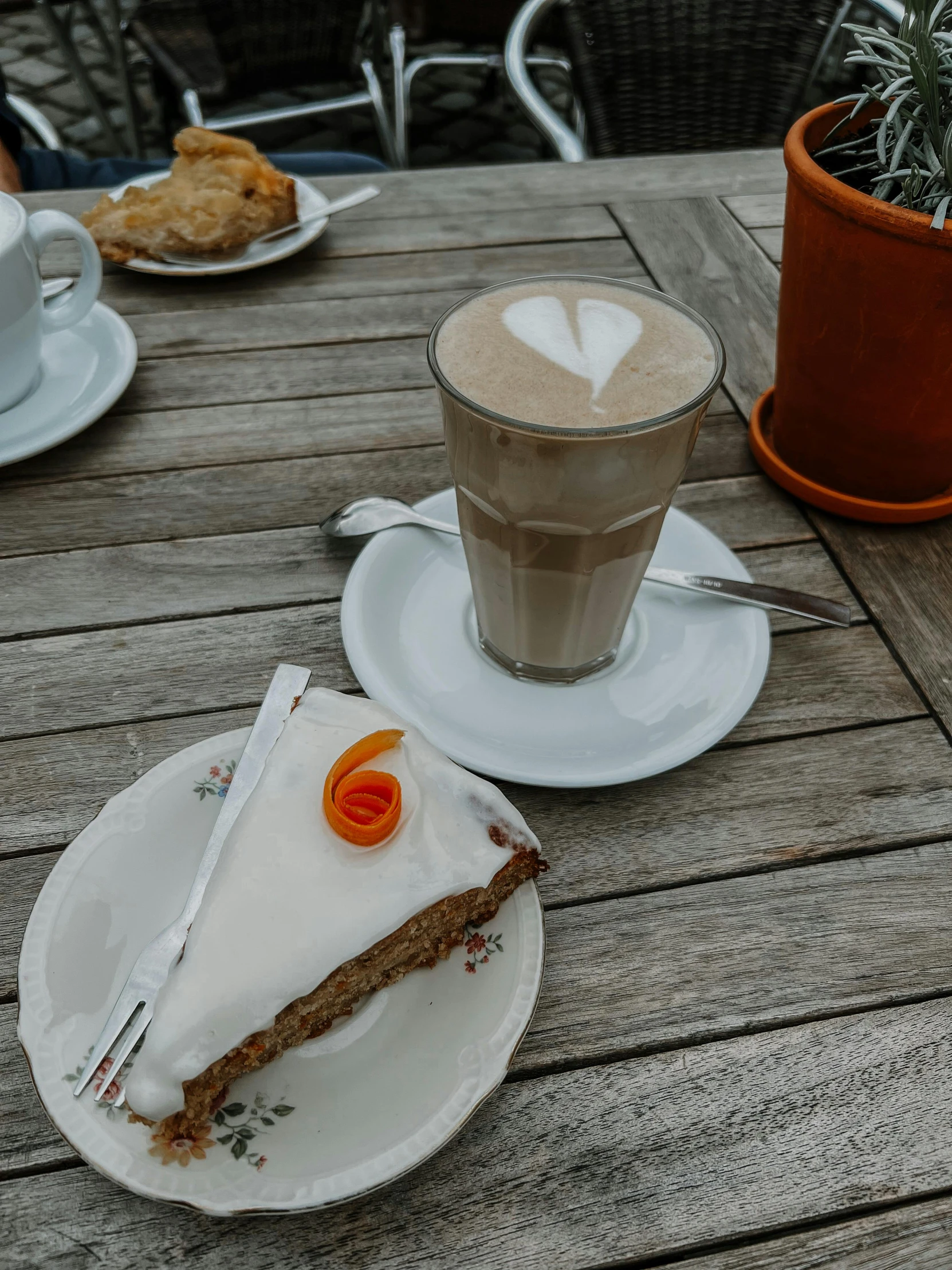 a slice of cake is on a plate next to two cups of coffee