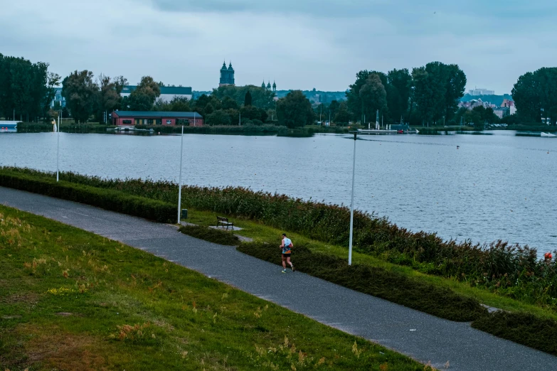 a man is walking down the path by the water