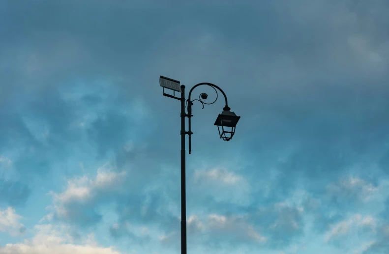 the street lamp is lit against the blue sky