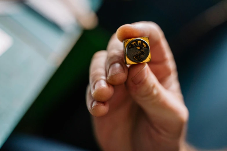 a hand holds a small yellow and black ring