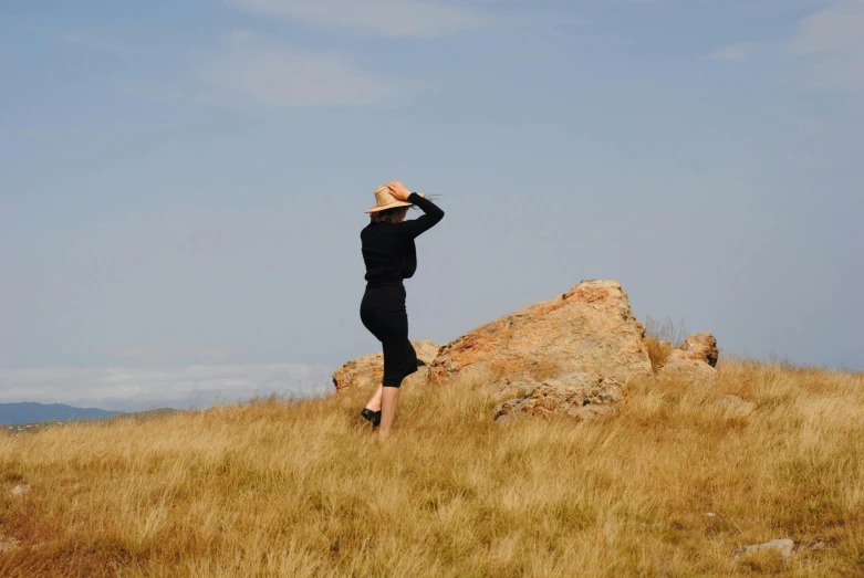 a person in a black jacket standing near a rock