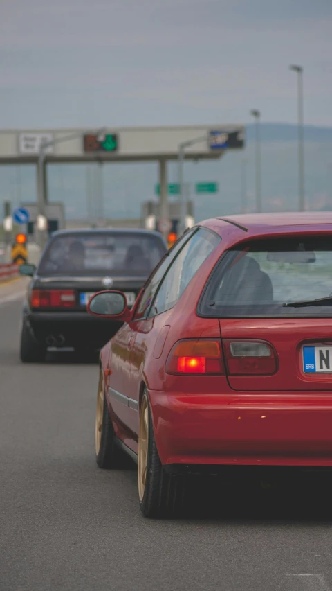 a red car stopped at a traffic light with ocean in the background