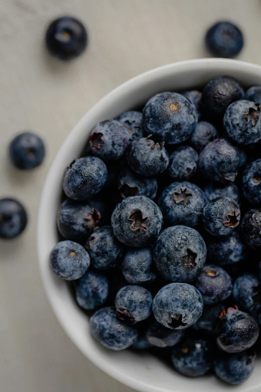 a bowl filled with lots of blueberries on top of a table