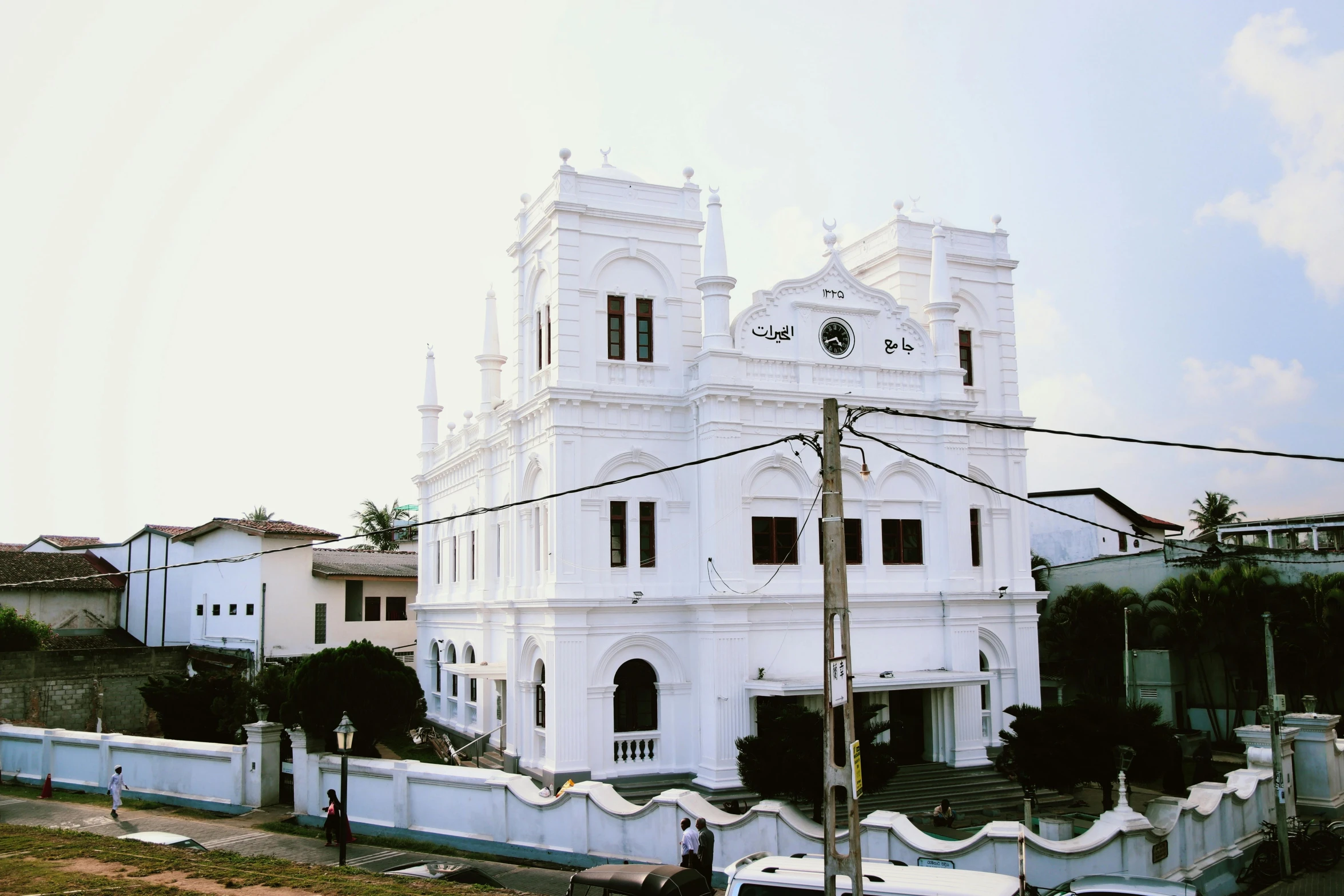 a street in front of a building with a white color and very large spire