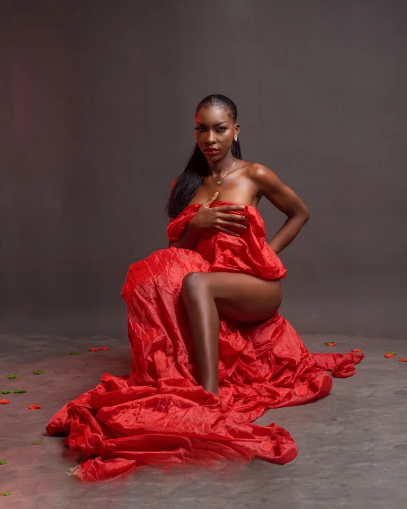 the young black woman is sitting in the floor covered with rose petals