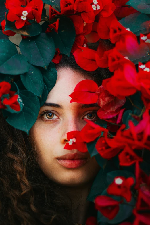a girl is hiding her head in a flowered wreath