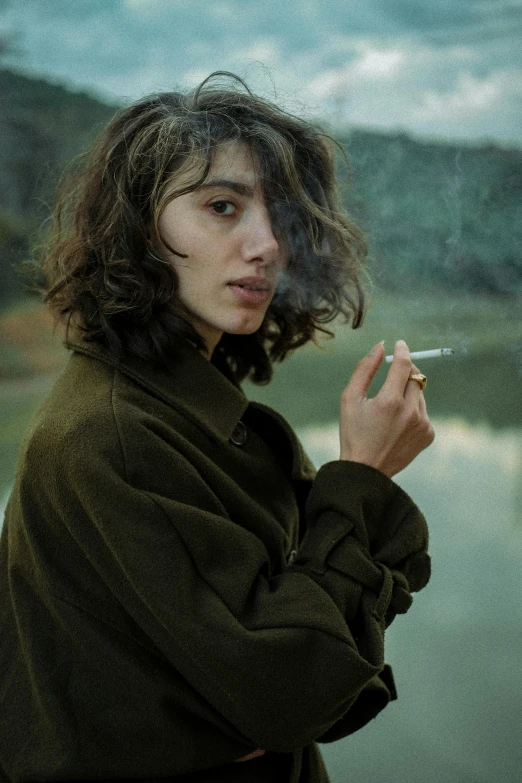 a woman smoking a cigarette by the ocean