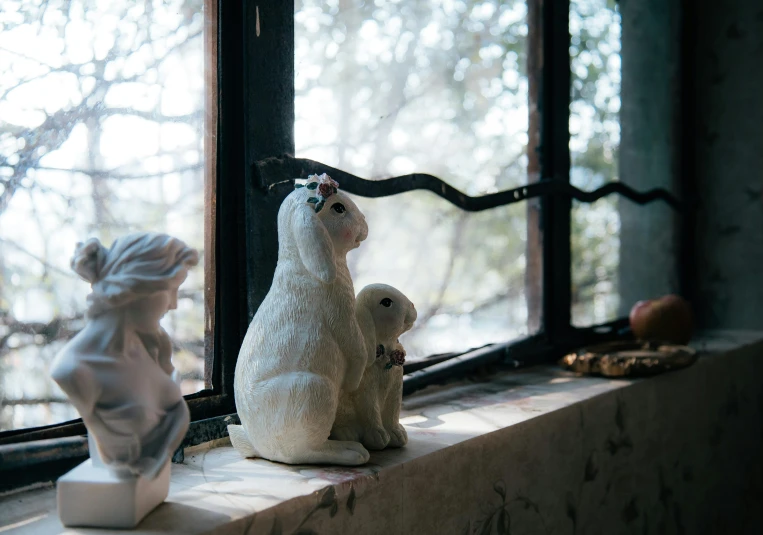 three plastic white rabbits sitting in front of window