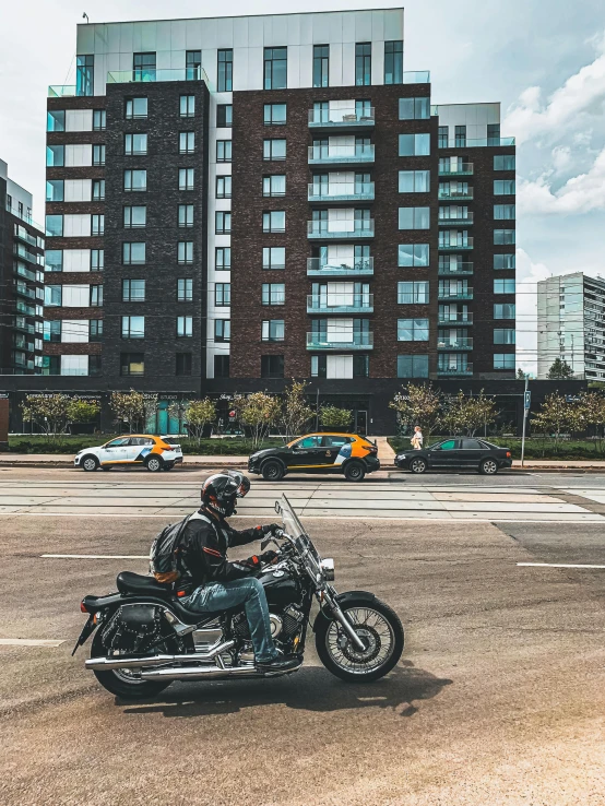 a motorcycle rider driving down a street in front of a high rise building