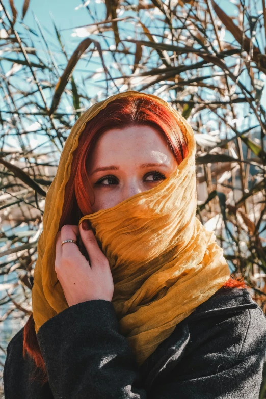 a woman with bright red hair wearing a scarf around her head