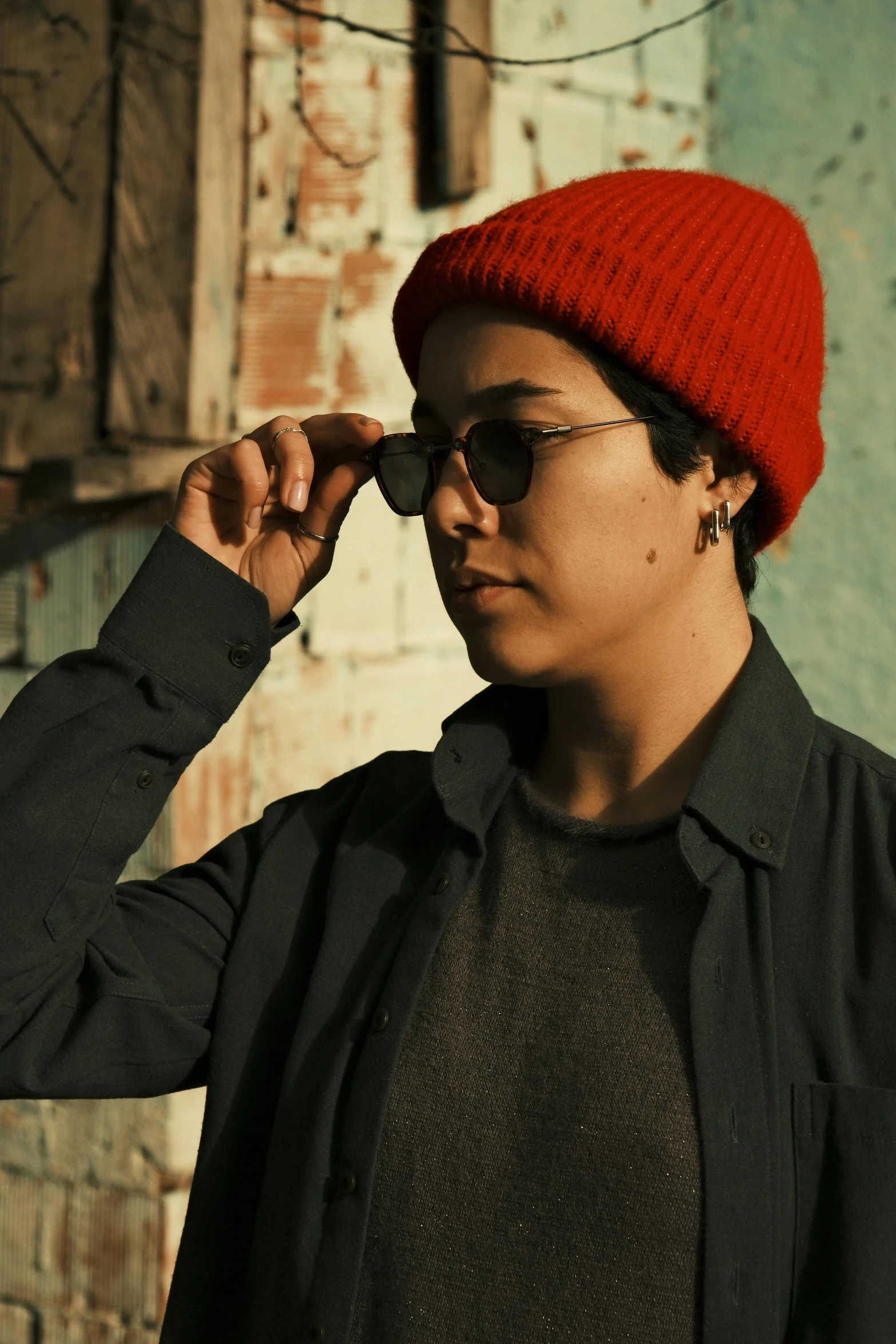 a young woman adjusts her red hat with dark glasses