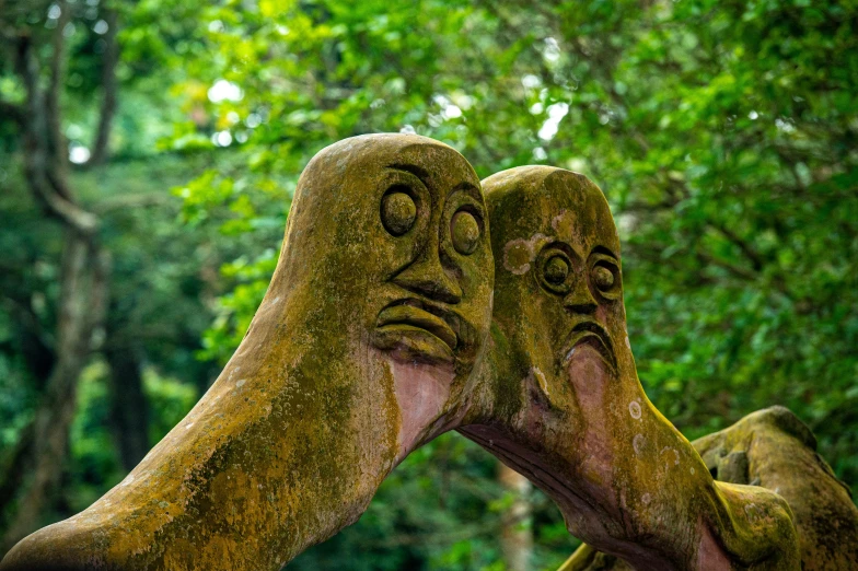 a pair of hands that are next to a statue of faces