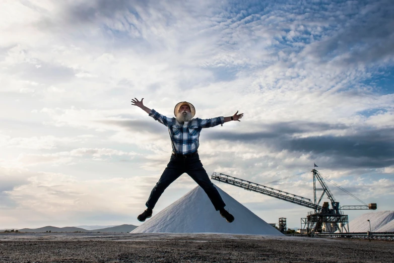 the man jumps in the air outside with his hands outstretched