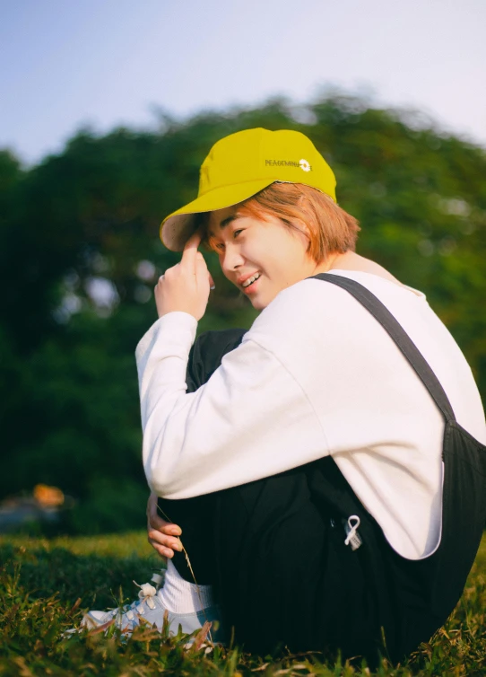 a person in a yellow cap is sitting in the grass