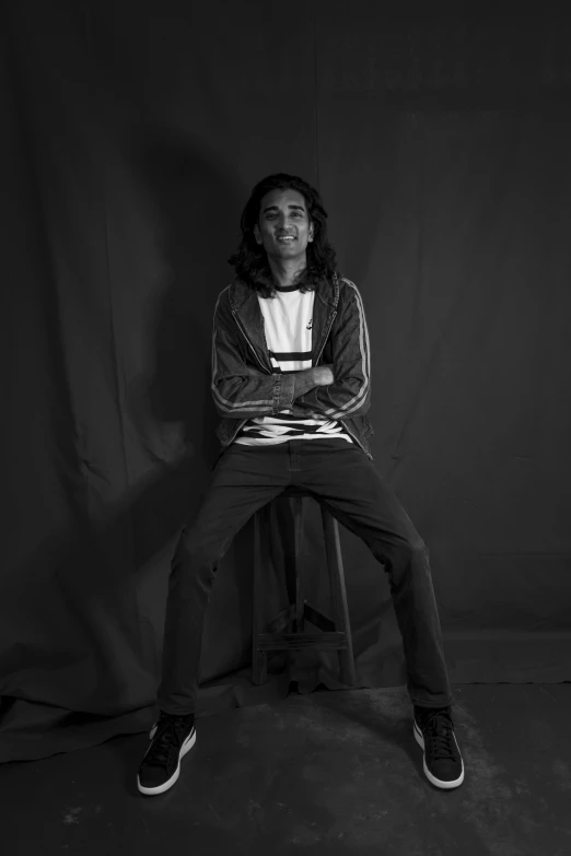 a young man sitting on top of a stool