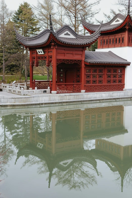 a large pool surrounded by trees, with an oriental building in the back