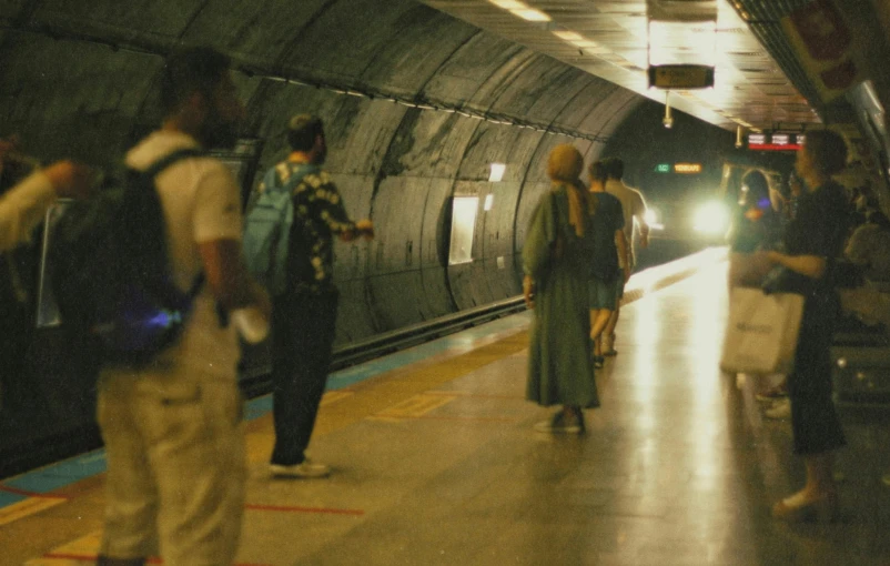 a train is waiting at a station as several people look on