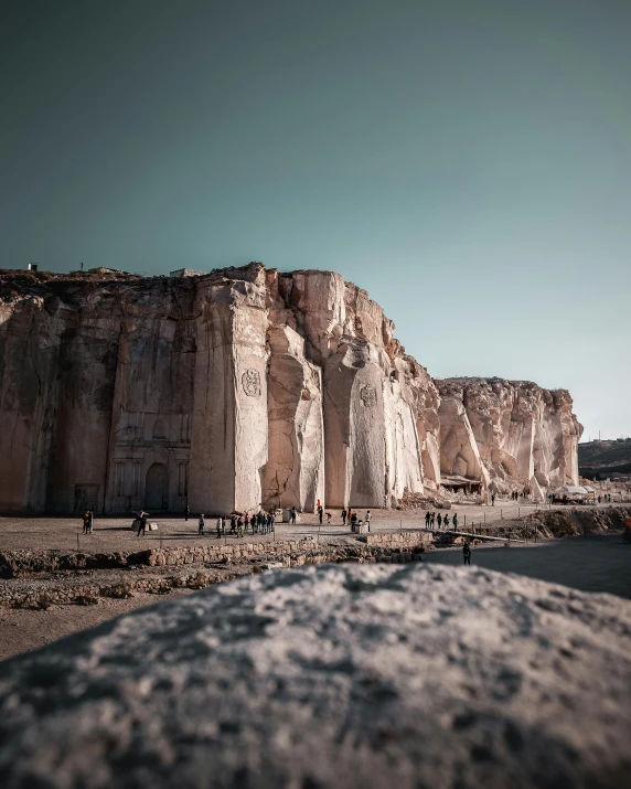 the people walk through the rocky landscape near the cliffs