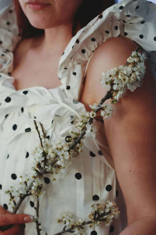 woman in polka dot print dress holding nch with buds