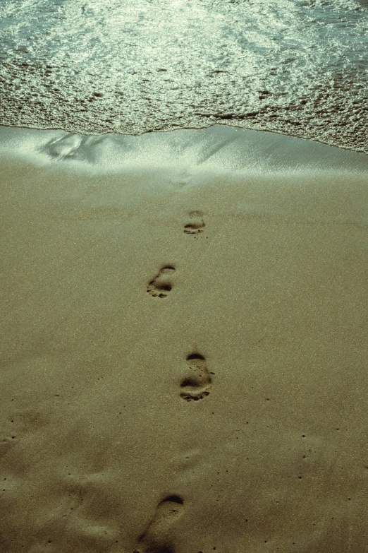 footprints left on sand by the water in front of an ocean