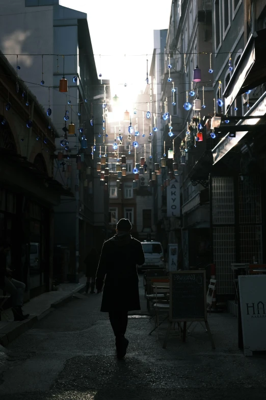 the woman walking on the sidewalk in the alley way is illuminated by the sunlight