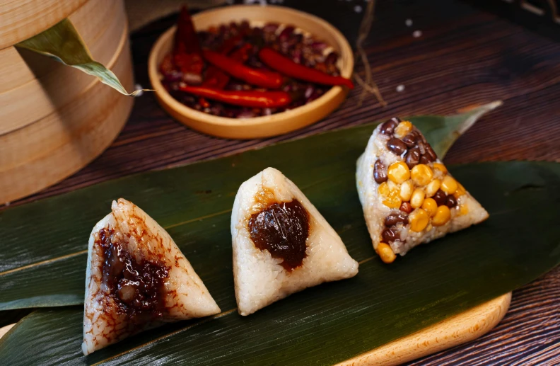 four desserts on a long leaf, one is filled with sauce