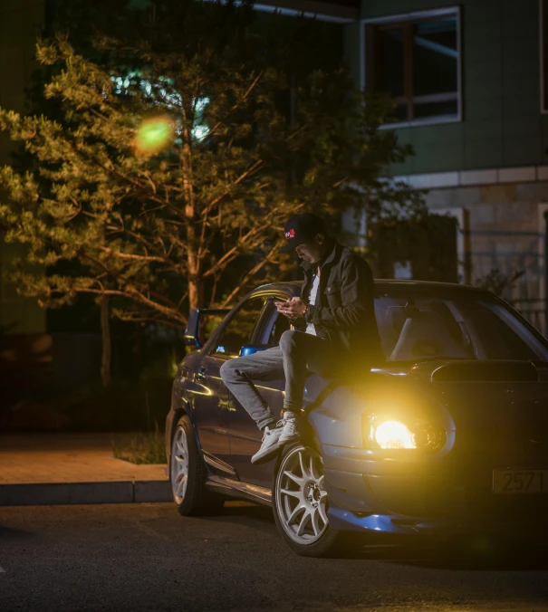 a man sitting on the hood of a car at night