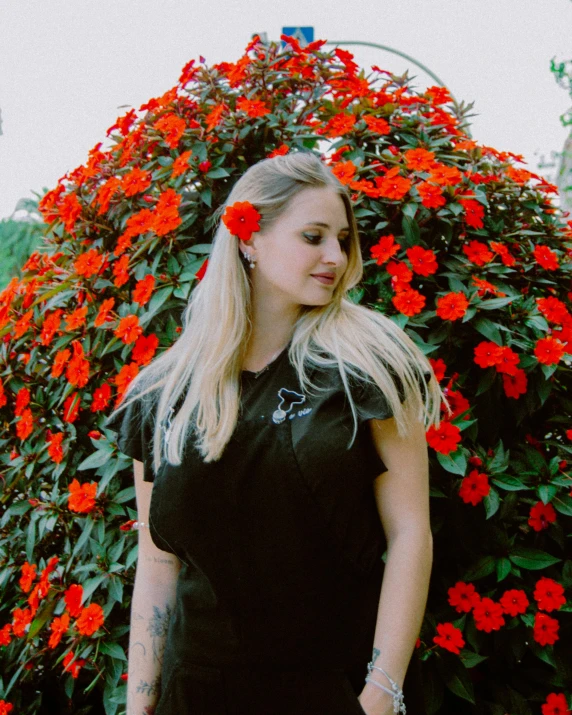 there is a woman standing next to a flower bush