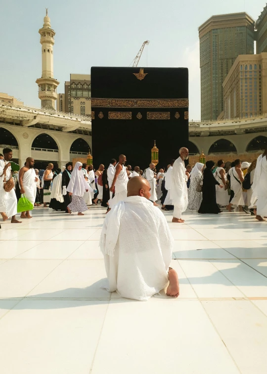 a group of people in white dress are kneeling in the center of a large area