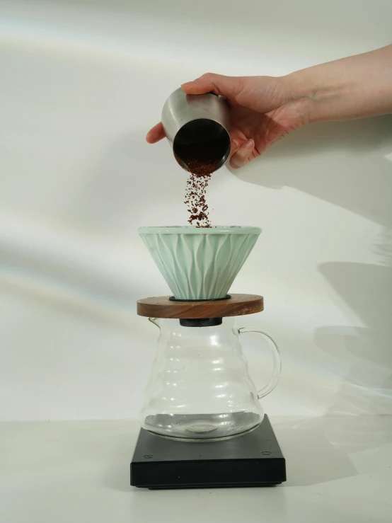 a person pouring a pour - over coffee into a glass carafe