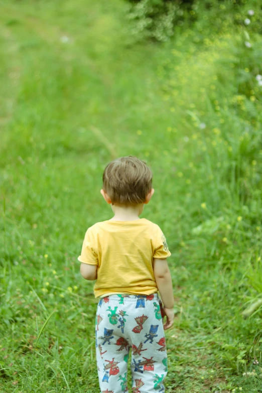 a boy in yellow shirt walking on grass