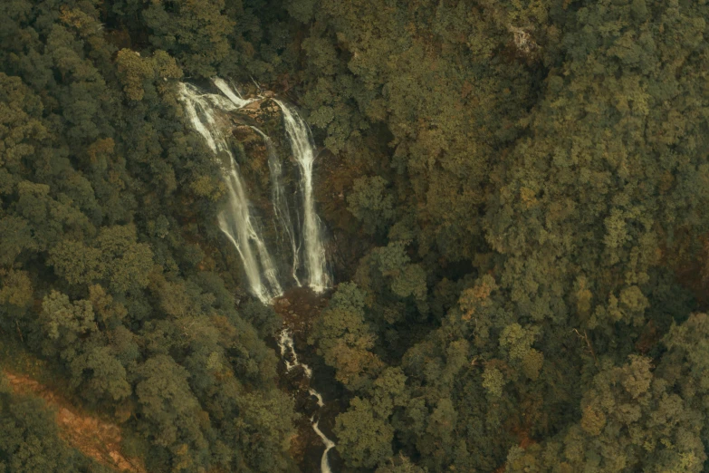 an aerial view of a waterfall in the middle of some trees