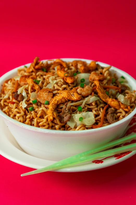 a bowl filled with rice and meat on a pink surface