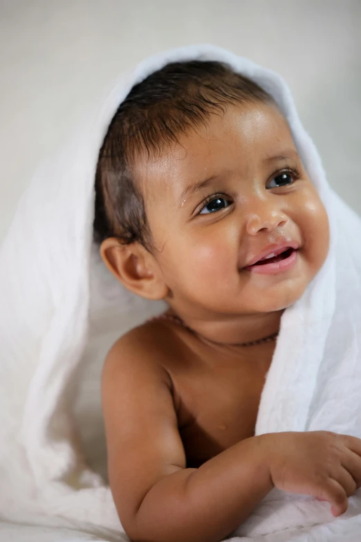 a baby covered in a towel smiles