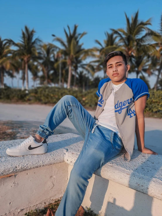 man sitting on cement ledge next to palm trees