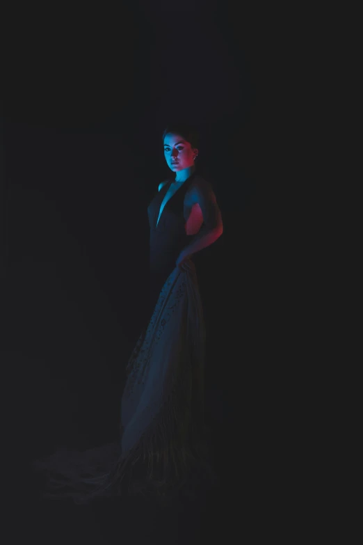 a woman standing on black ground in a dark room