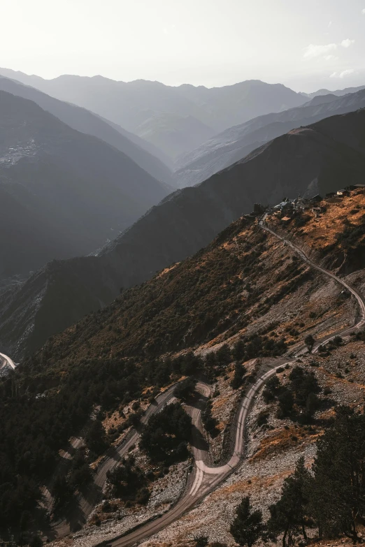 the top of a hill with a narrow road on one side and the view of the mountains in the distance